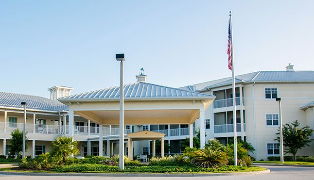 Senior living community, Water's Edge of Lake Wales, featuring urban architecture and lush greenery.