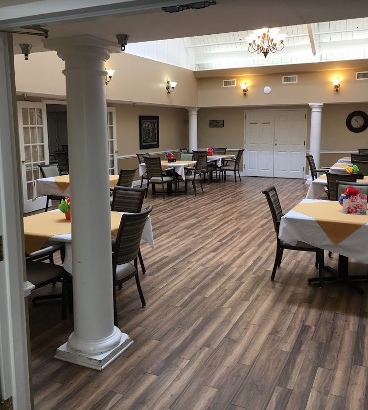 Interior view of The Gardens of Waterford senior living community featuring hardwood flooring, dining area, and art.